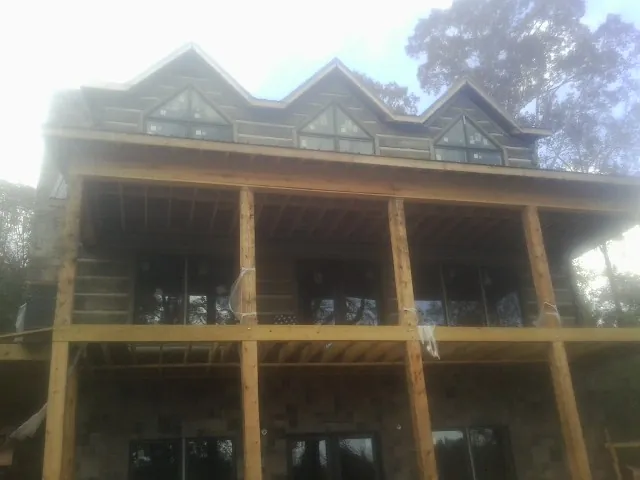 Dormers and porch framing on a large log home under construction — Roof Coating work by our crew in Lorton