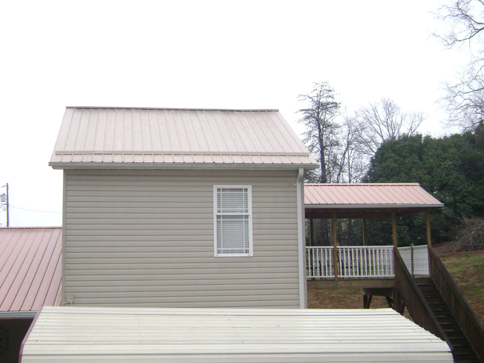 Tan metal roofs on a two story addition and attached porch, from a Roof Replacement job in Lorton